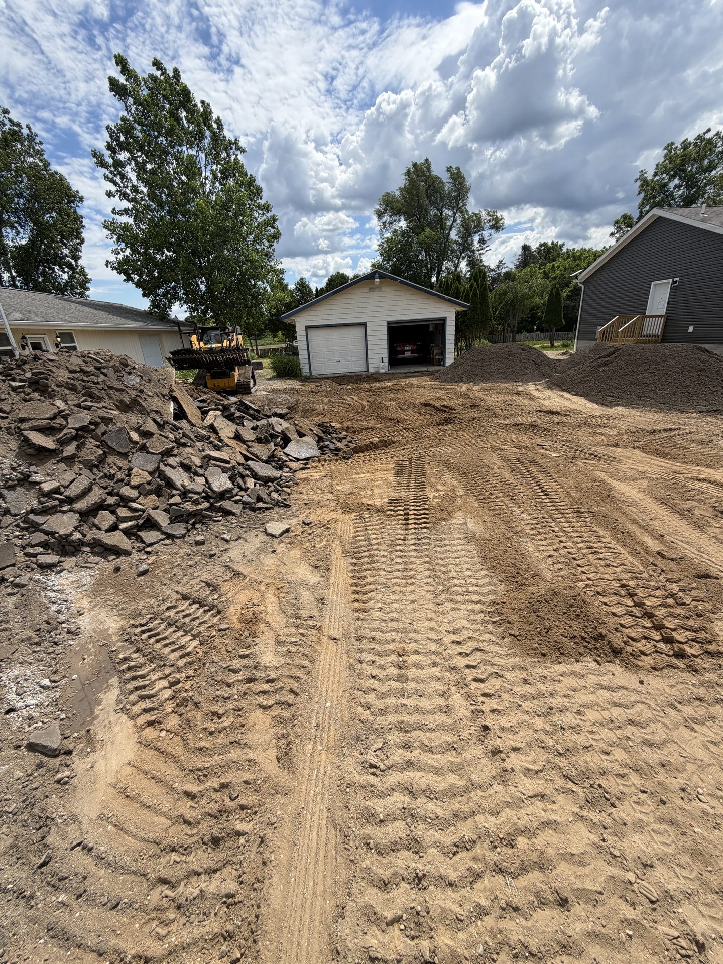 Skid steer removing old asphalt and prepping a driveway base in Jackson County