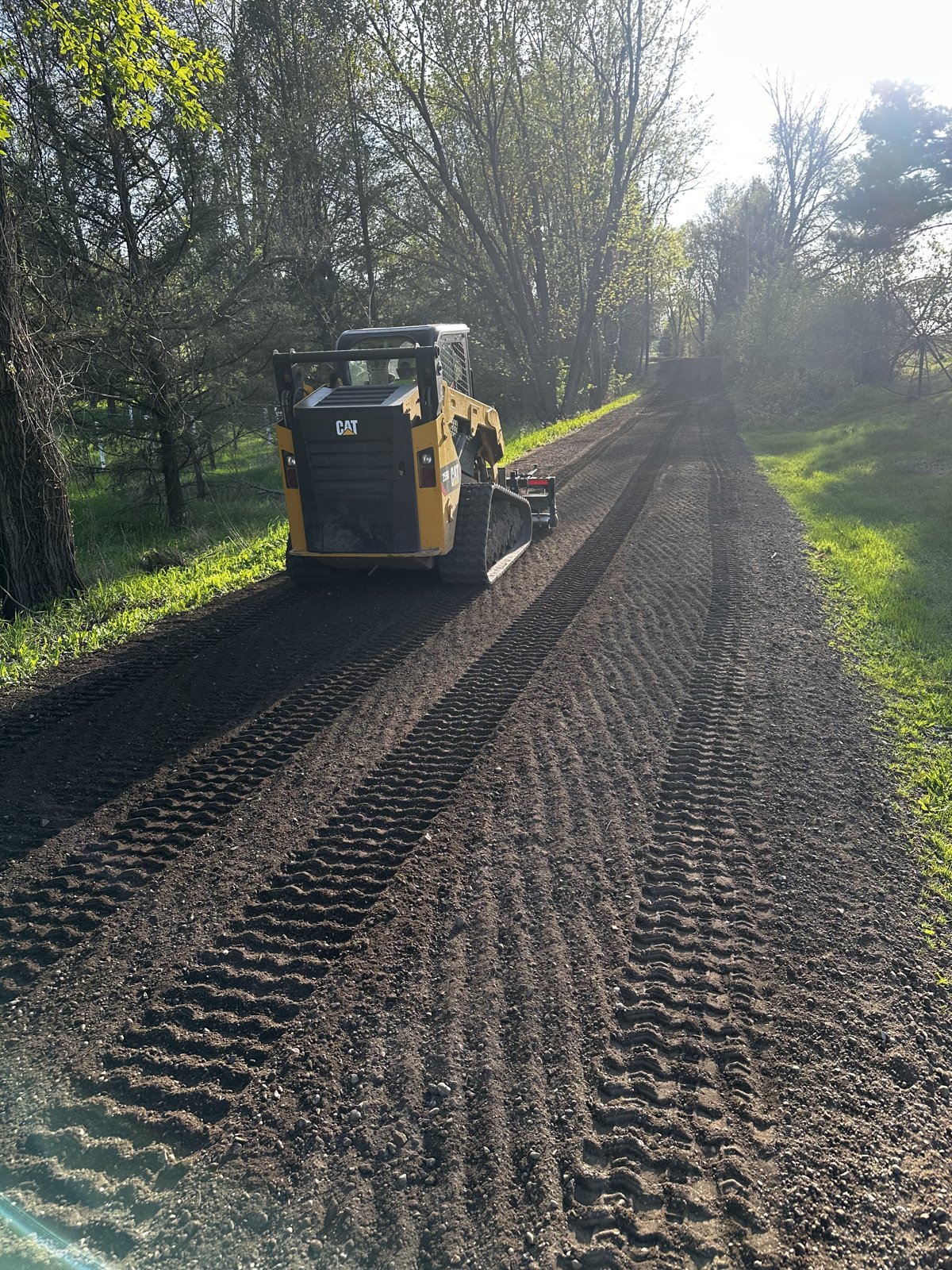 CAT skid steer grading a long dirt driveway in Jackson County